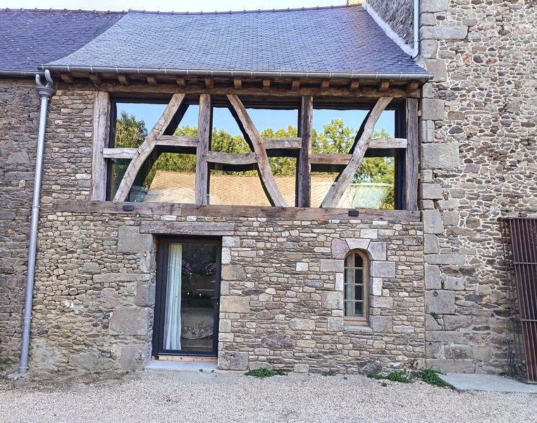 Baie coulissante aluminium anthracite intégrée derrière le colombage, façade en pierre de schiste