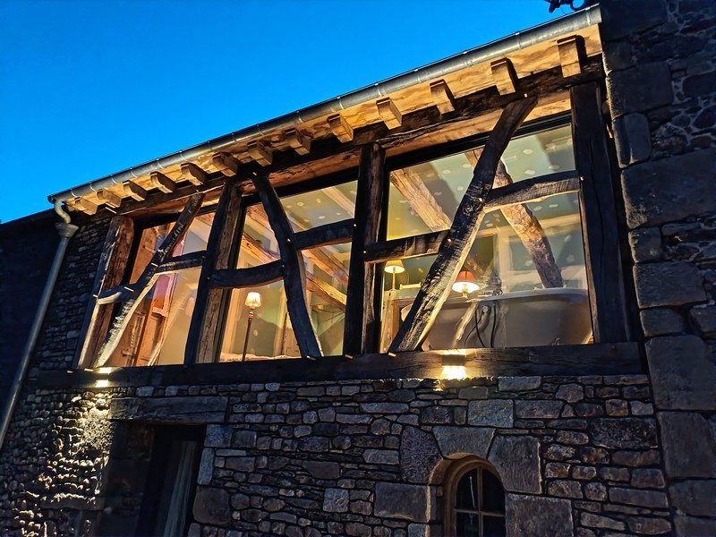 Châssis aluminium posé derrière un pan de bois ancien, détail de nuit en contre-jour