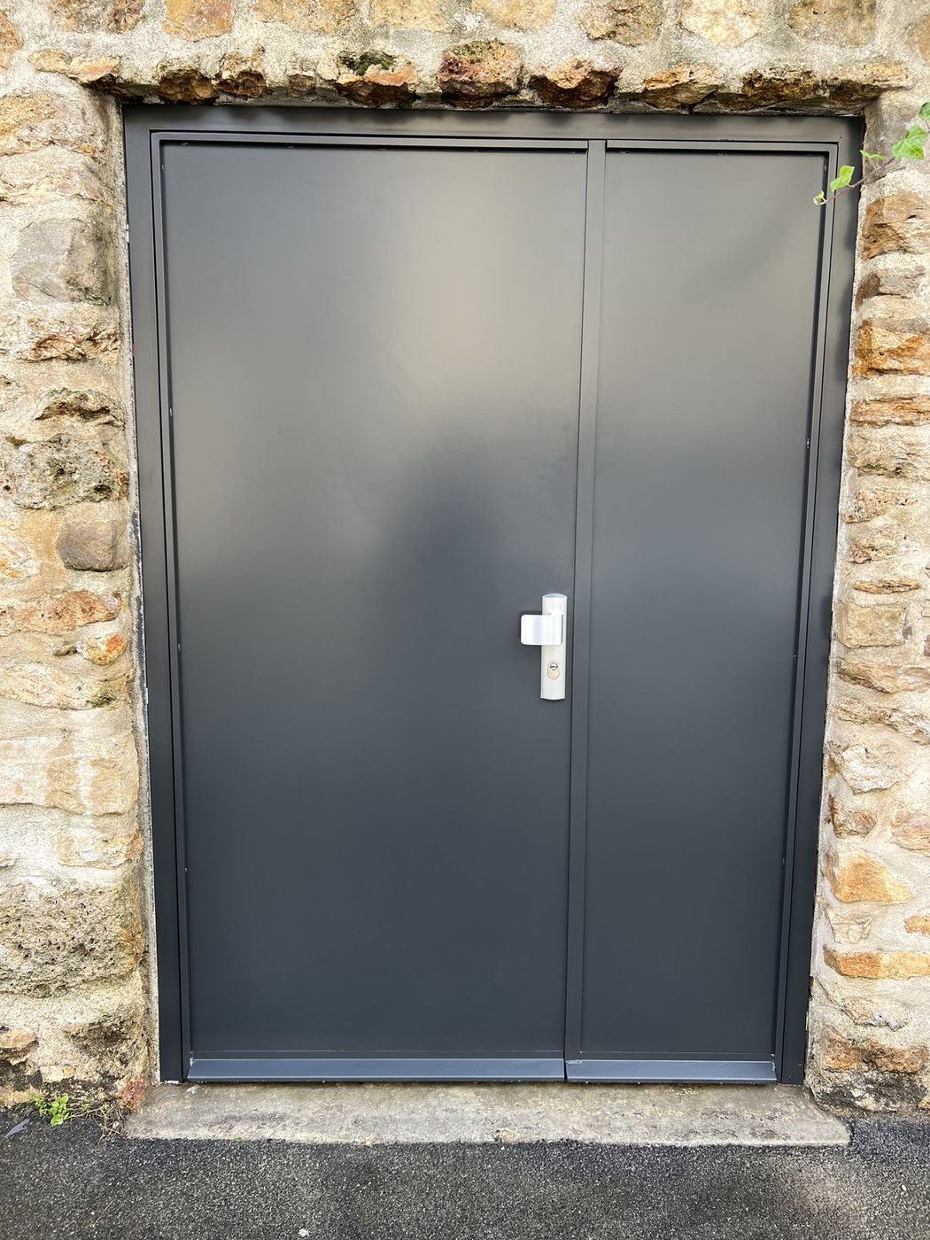 Porte double vantaux acier anthracite sur mesure dans mur en pierre