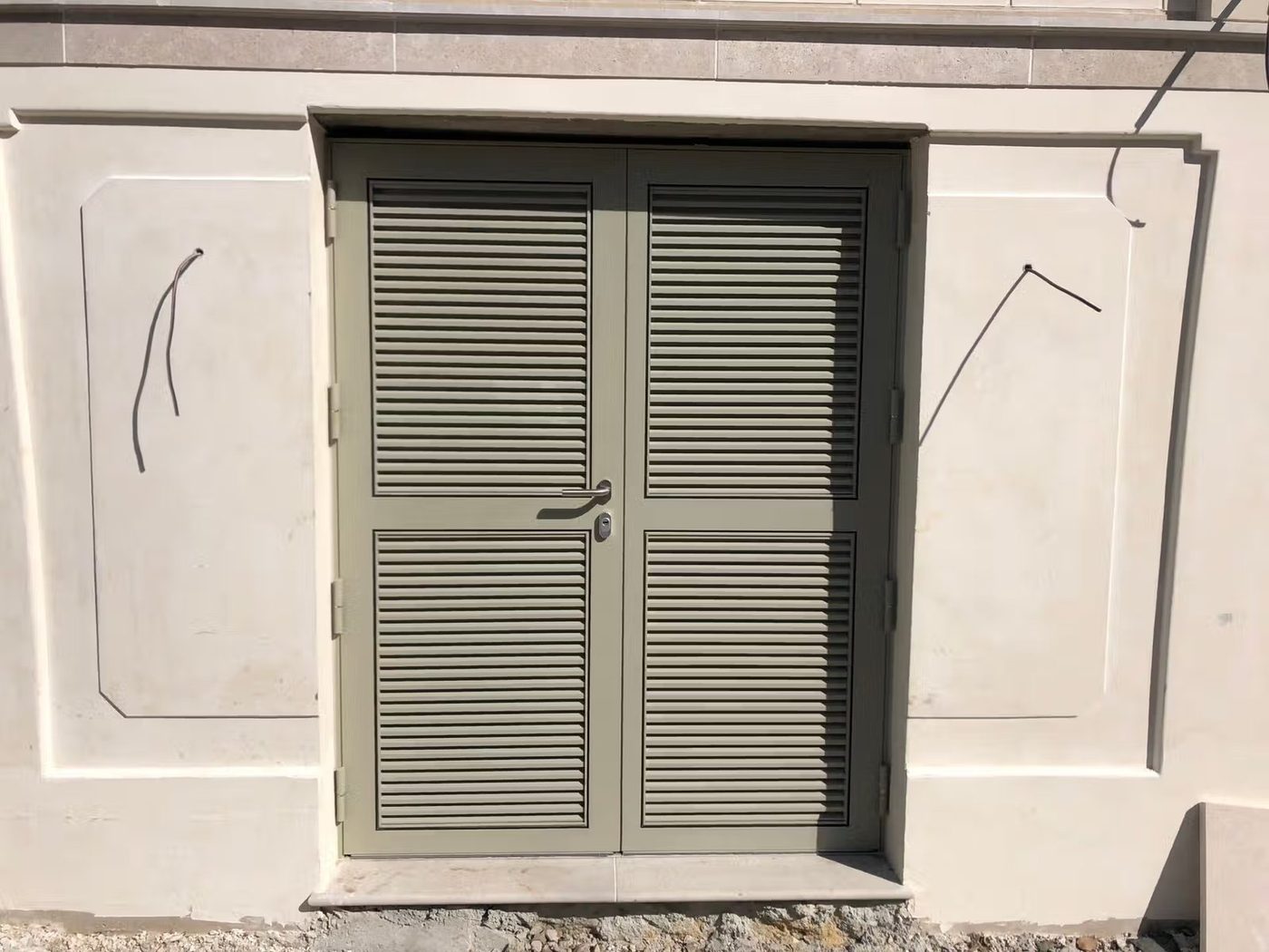 Porte double vantaux à persiennes métalliques grises, façade en pierre de taille — EloxyMetal