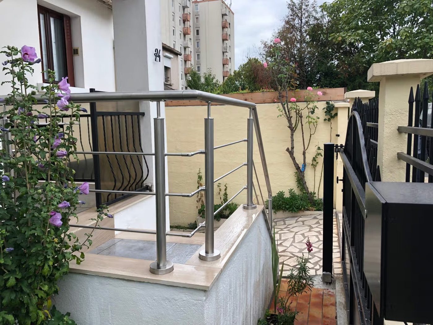 Rampe inox tubulaire et portail métal noir à l'entrée d'un jardin — EloxyMetal
