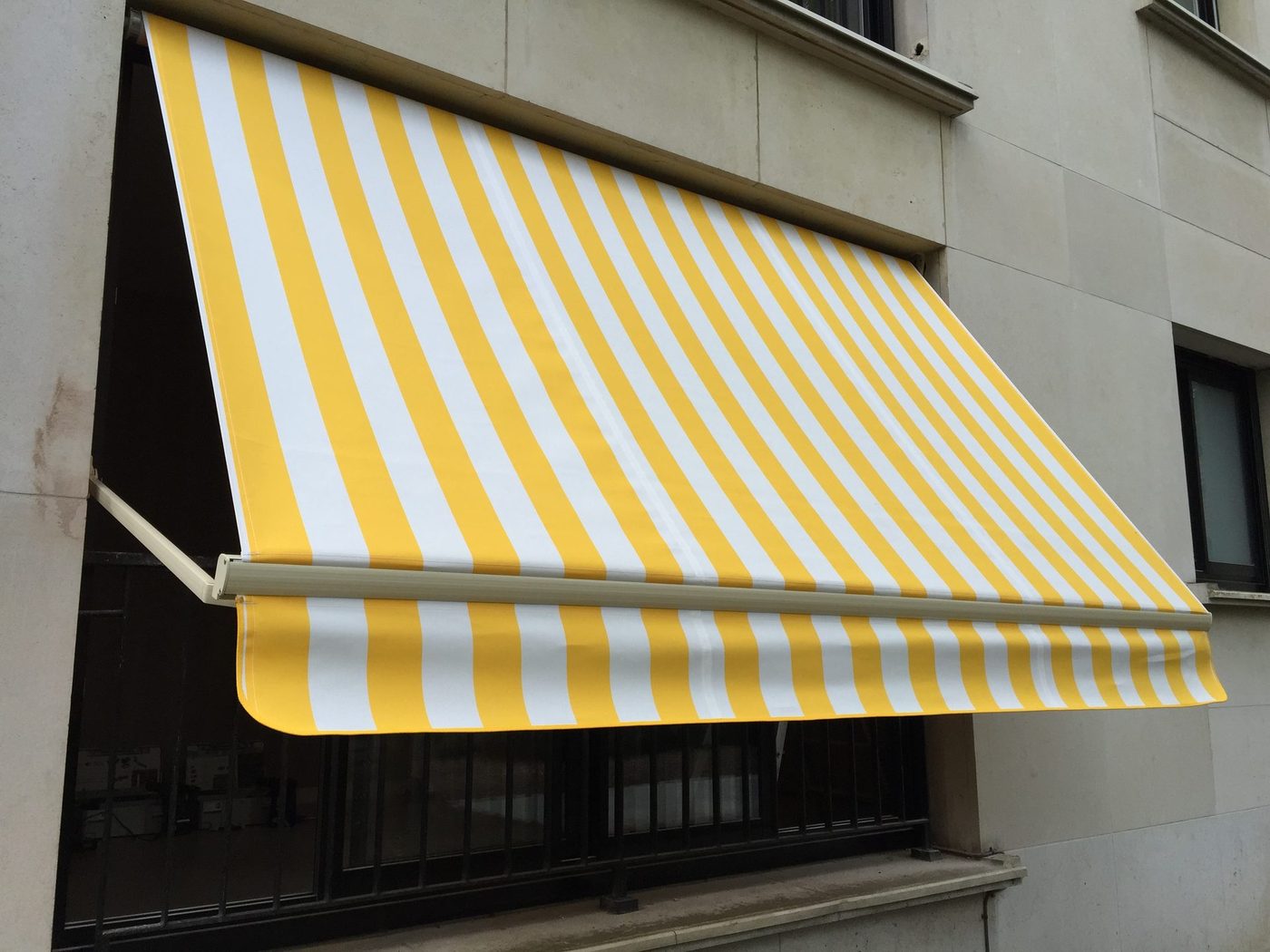 Store-bannette coffre à toile rayée sur la façade d'un immeuble — EloxyMetal