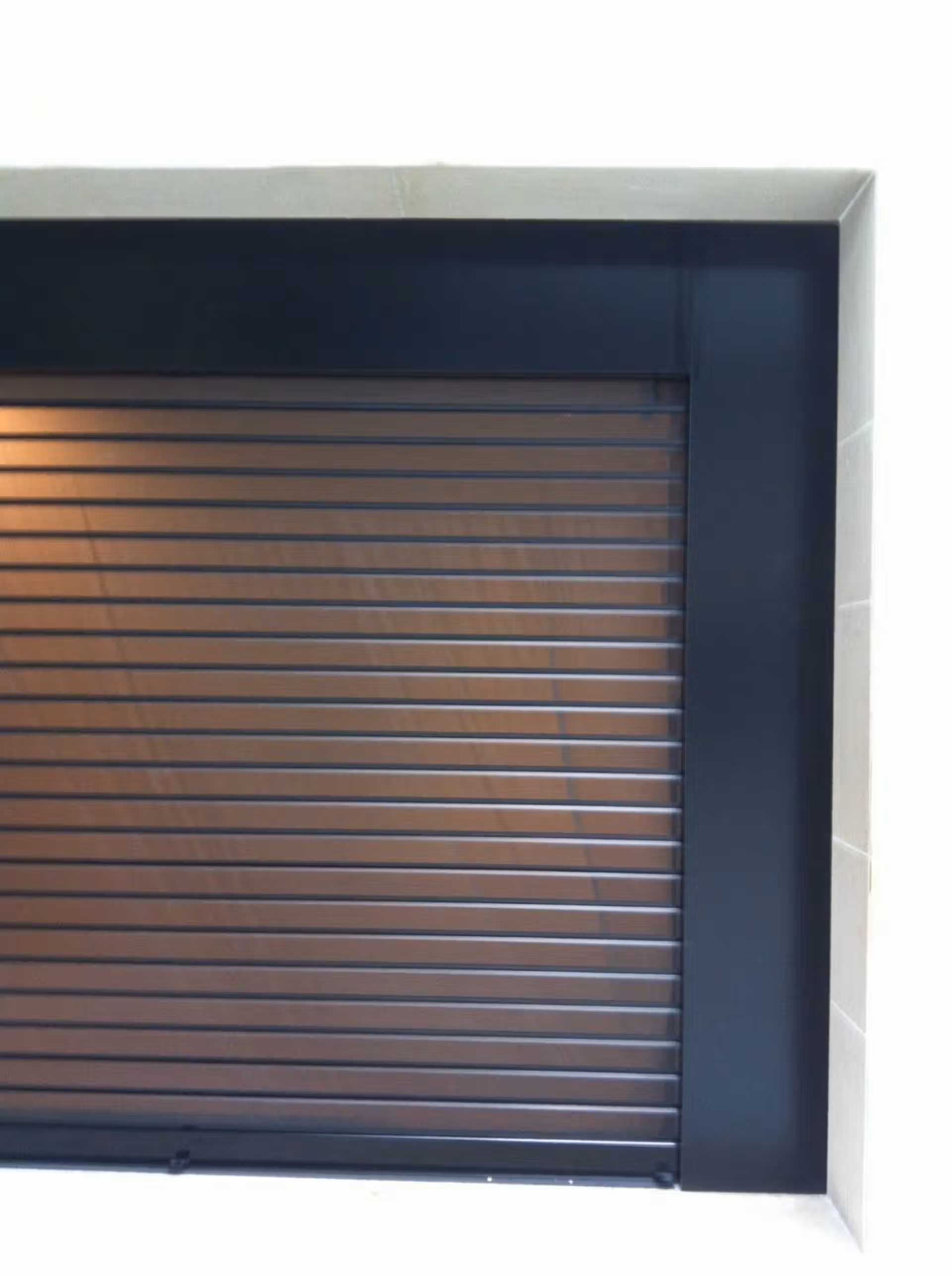 Gros plan sur le tablier d'un rideau métallique à lames orientables en aluminium noir mat avec coffre et encadrement anthracite